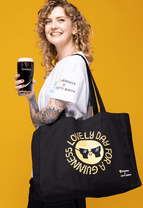 Fatti Burke holding a pint of Guinness Draught for the mast-have summers clothing, accessories and prints summer collection designed for Guinness.