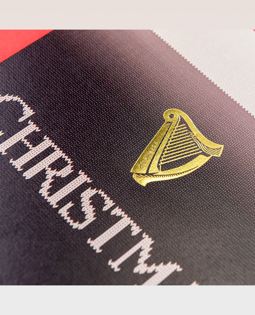 Close-up of a black fabric with 'Christian' text and gold harp logo.
