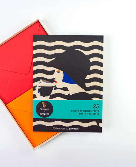 Pack of writing paper with envelopes featuring a design of a dog and a penguin, with a red and orange envelope on a white background.