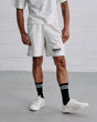 Man wearing a white t-shirt and shorts with 'Guinness' branding against a white brick wall.