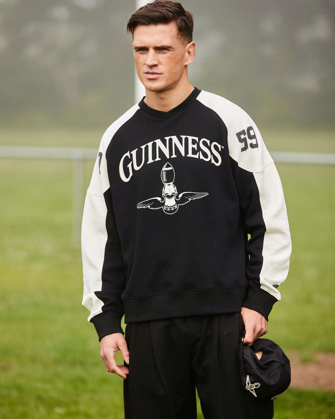 Man wearing a Guinness sweatshirt on a grassy field