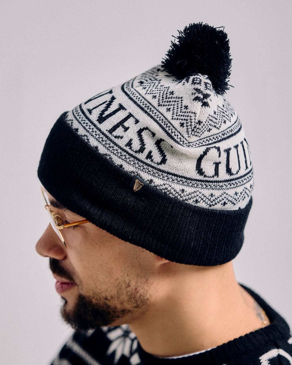 Person wearing a black and white patterned beanie with 'Guess' branding.