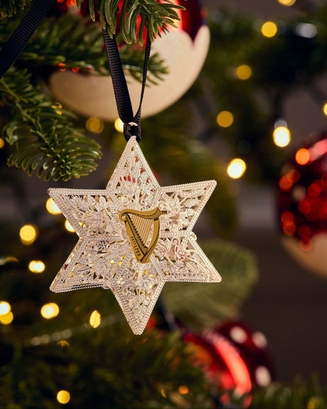 Decorative star ornament with a harp on a Christmas tree with lights in the background