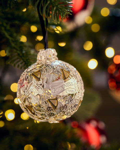 Decorative Christmas ornament on a tree with blurred lights in the background