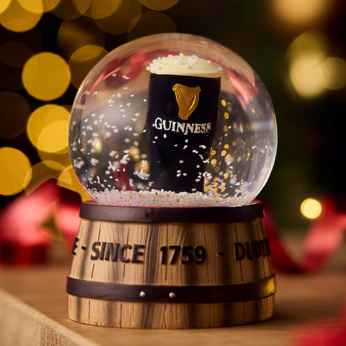 Snow globe with a Guinness pint inside, featuring the brand's logo and text, against a festive background.