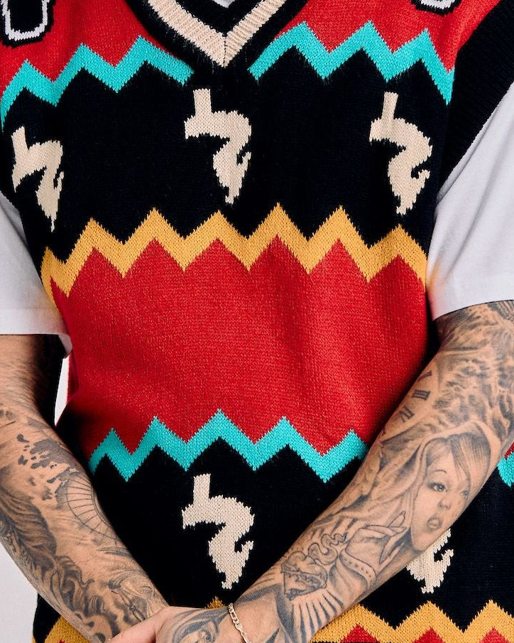 Man wearing a colorful patterned sweater vest over a white shirt against a light gray background