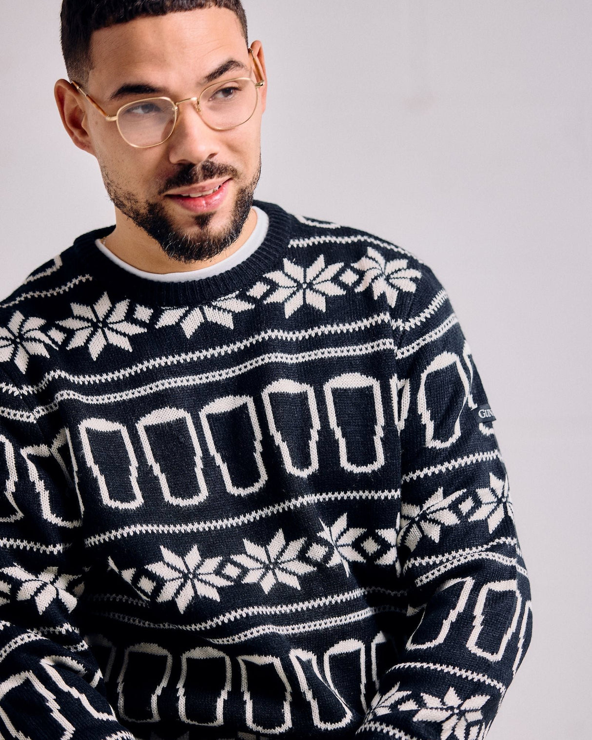 Man wearing a navy blue sweater with white geometric pattern against a plain background