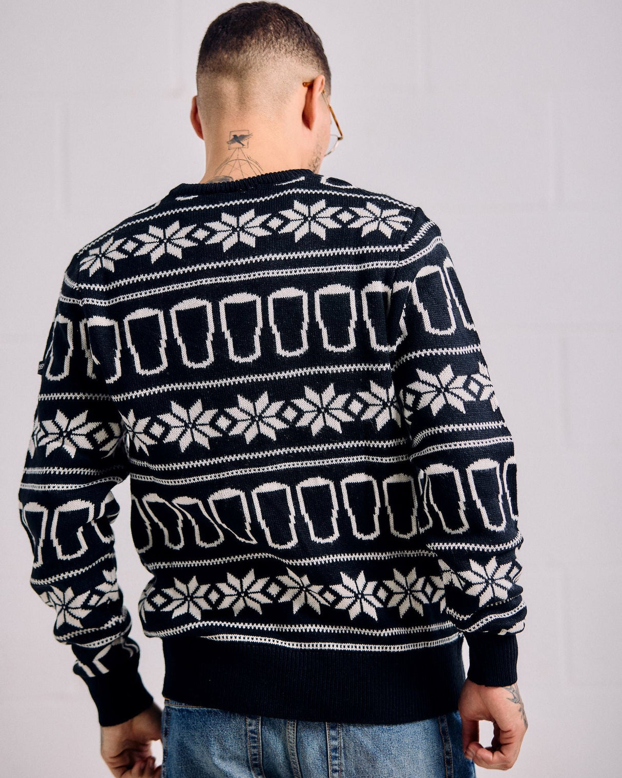 Person wearing a black sweater with white pattern against a plain background