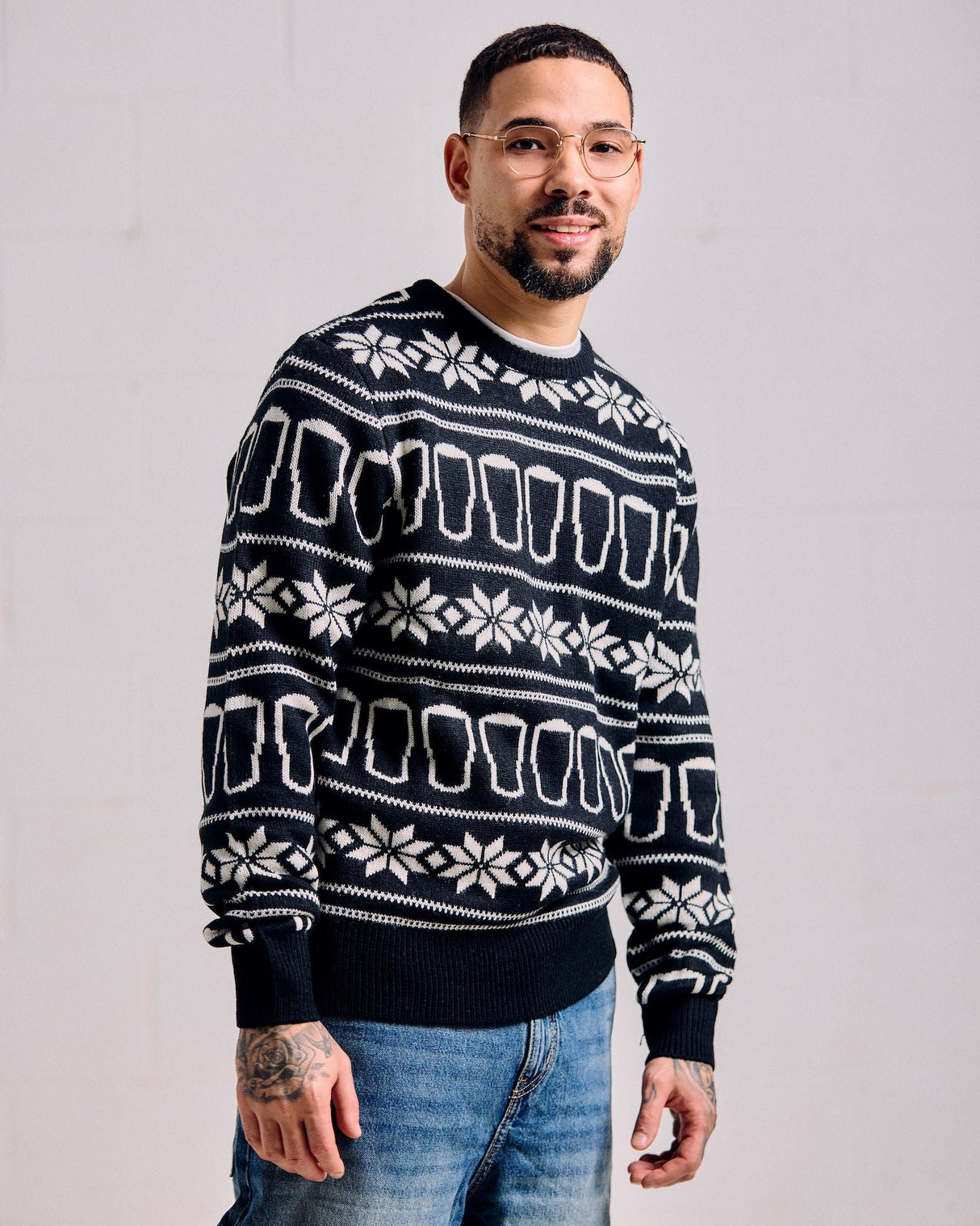 Man wearing a black sweater with white patterns against a plain background