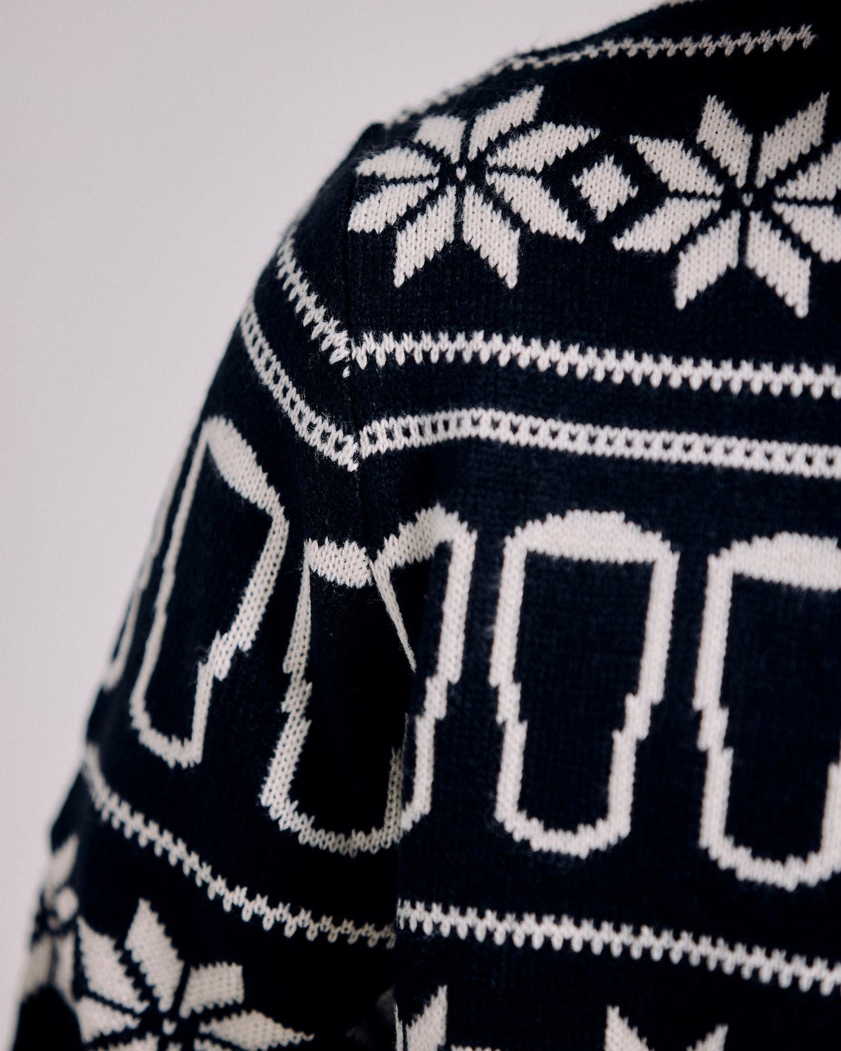 Close-up of a black sweater with white geometric pattern on a light gray background