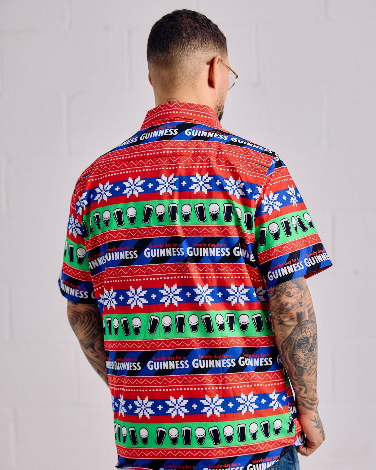 Person wearing a colorful Guinness shirt with a pattern of beer glasses on a plain background