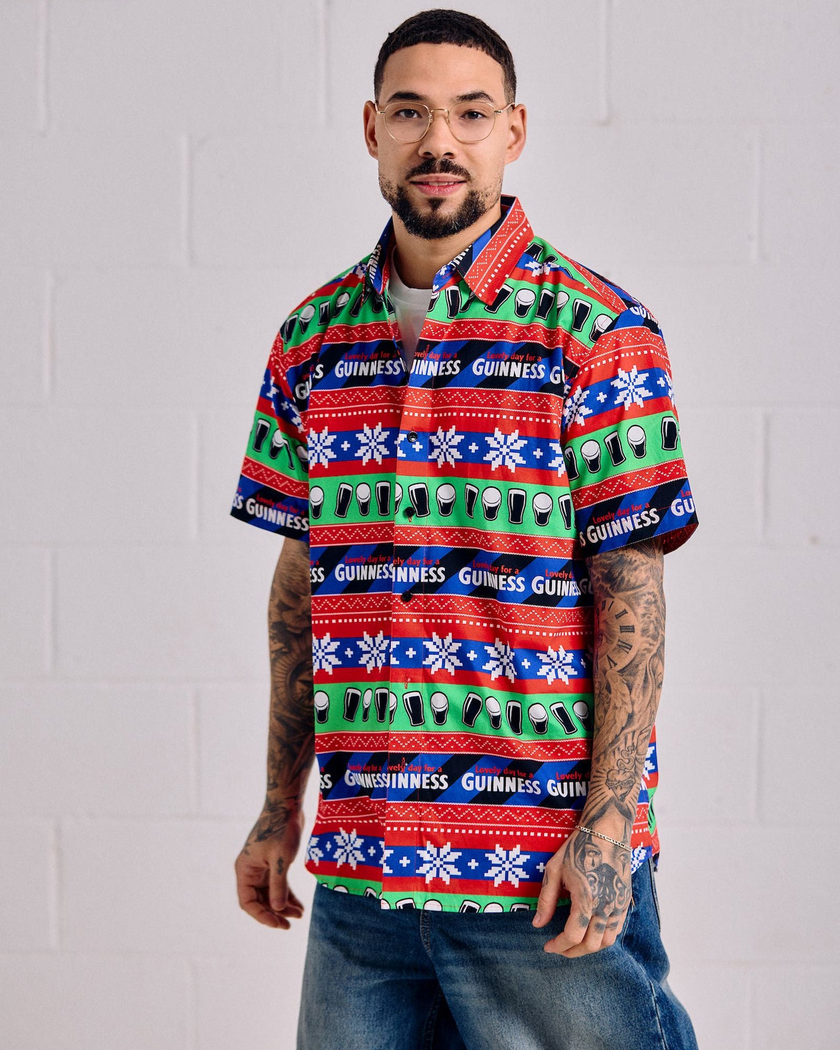 Man wearing a colorful patterned shirt with visible branding against a white background