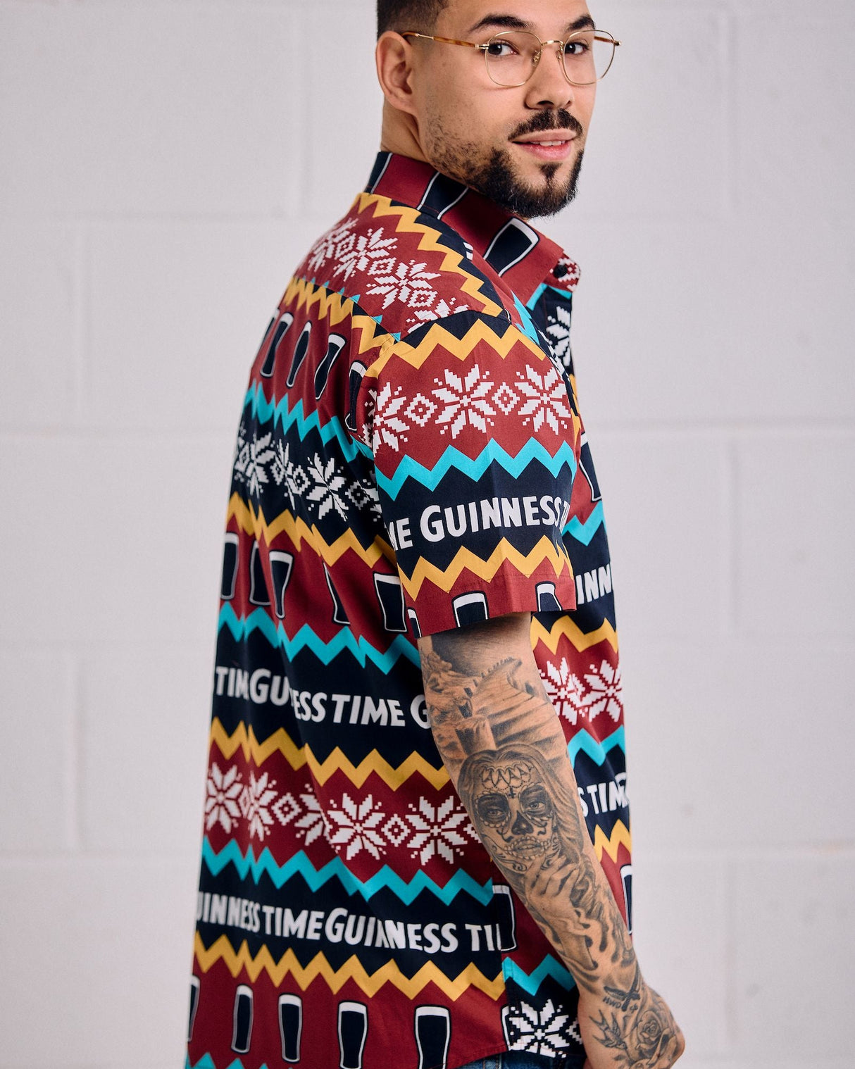 Person wearing a colorful Guinness-themed sweater against a plain background