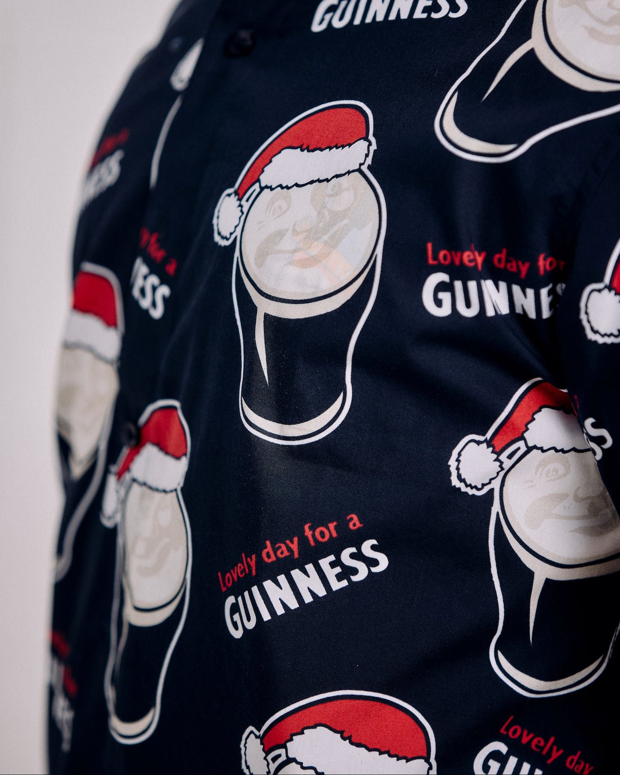 Navy blue shirt with white and red Guinness beer bottle graphics and text.