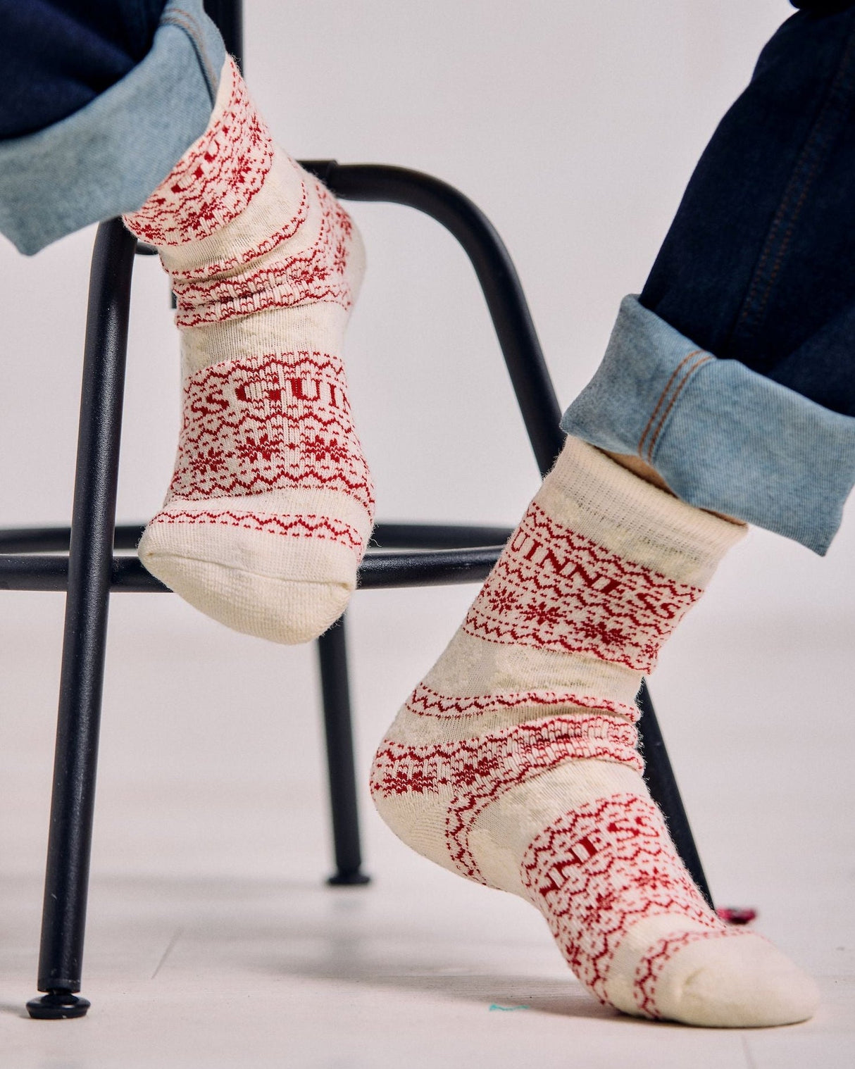 Person wearing patterned socks sitting on a chair with a light background