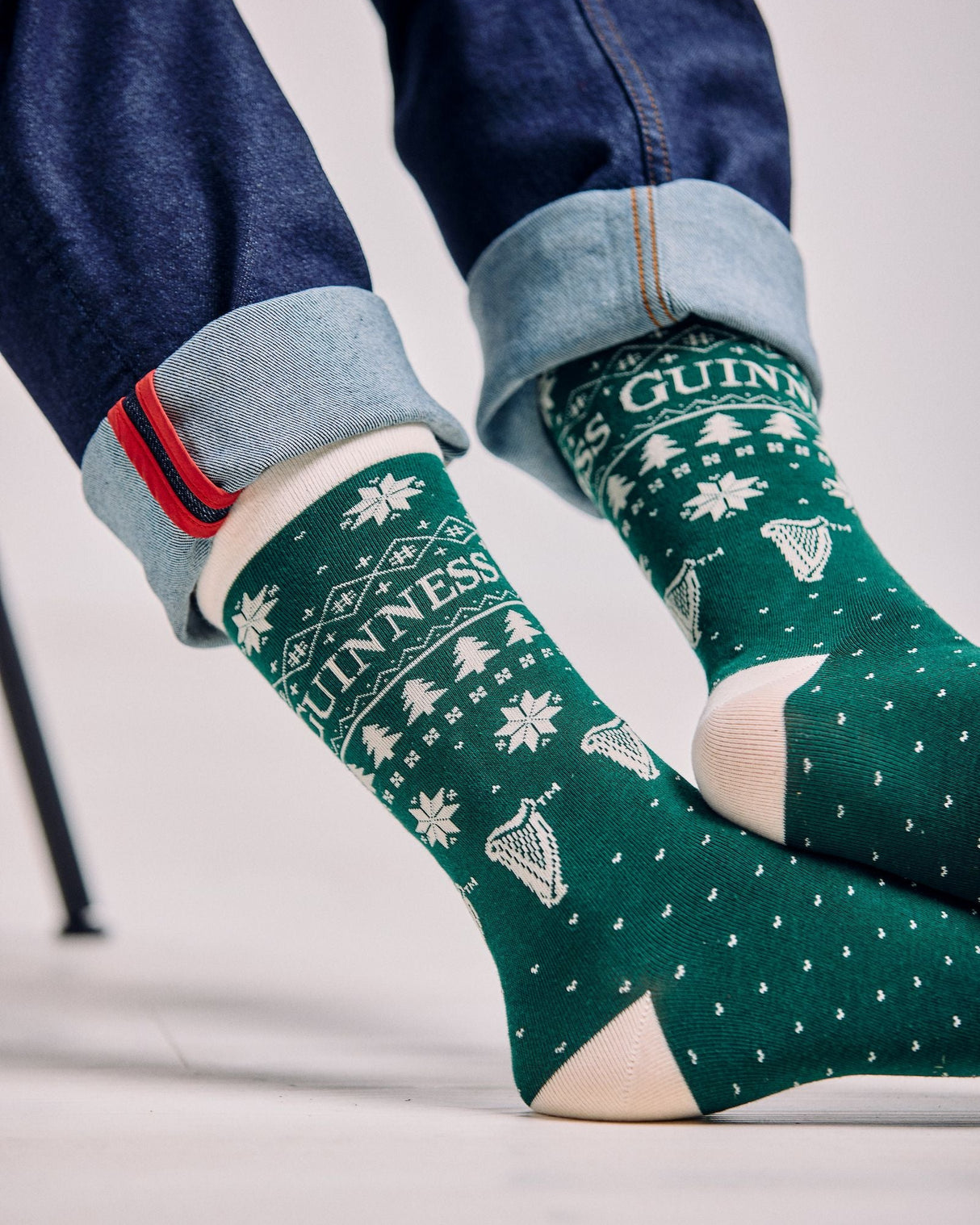 Green patterned socks with 'Guinness' branding worn with blue jeans.