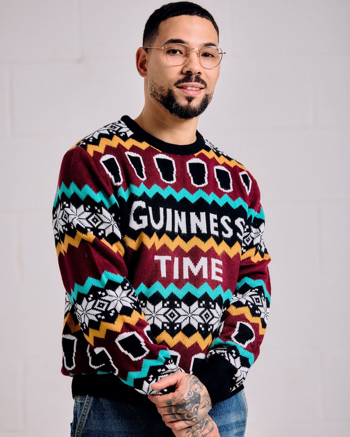 Person wearing a colorful sweater with 'Guinness Time' text against a plain background