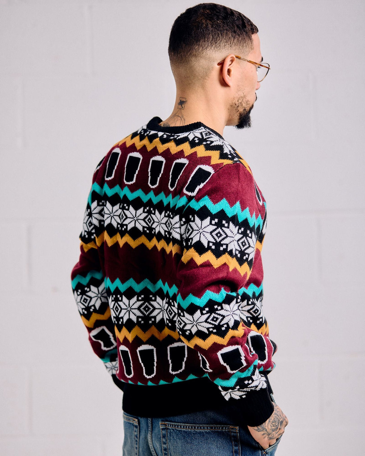 Person wearing a colorful patterned sweater against a plain background