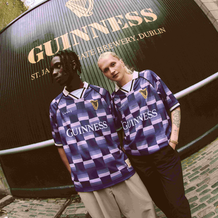 Image of a guy and a girl wearing Guinness x Art of Football jerseys in front of Guinness Gates.