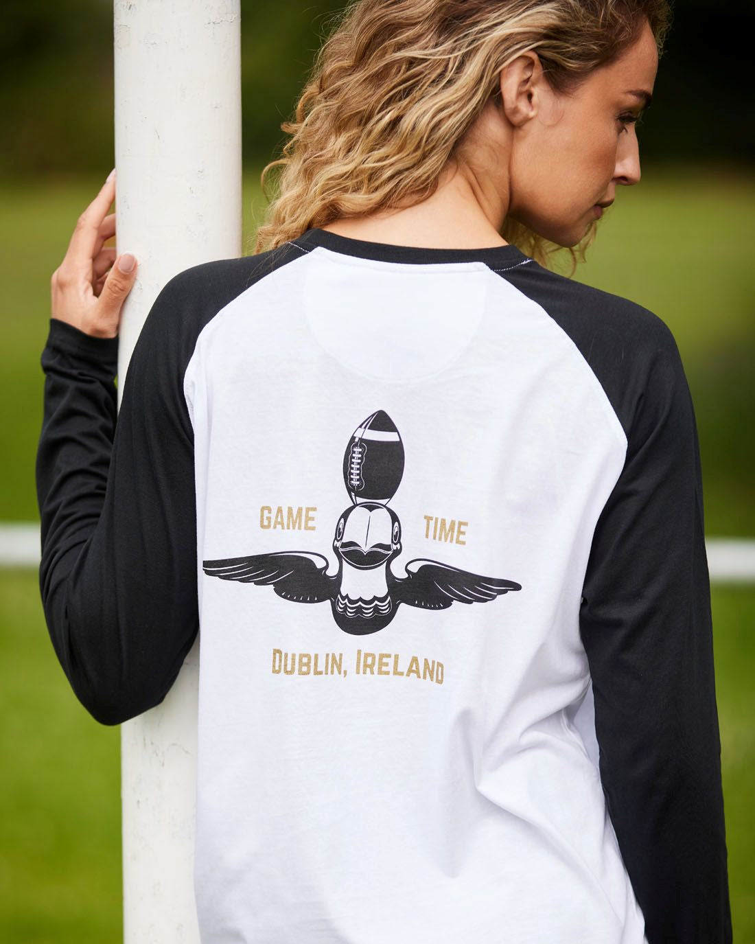 Person wearing a black and white long-sleeve shirt with a graphic design on the back, standing outdoors.