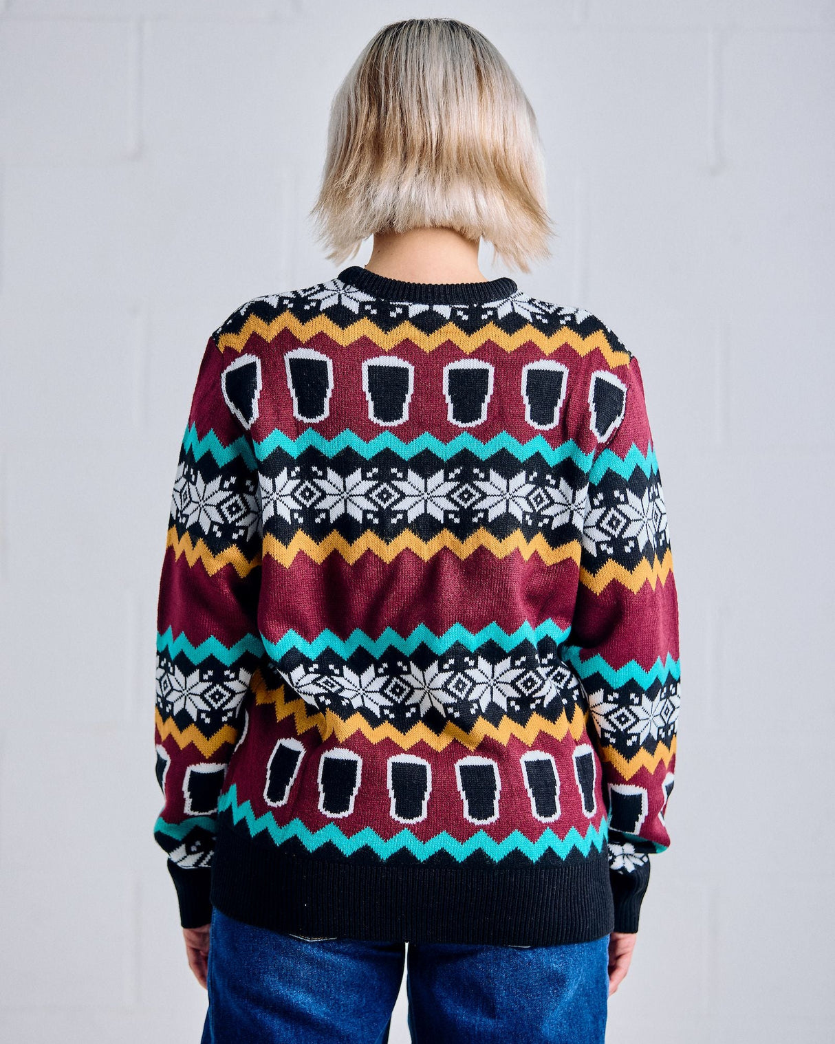 Person wearing a colorful patterned sweater against a plain background