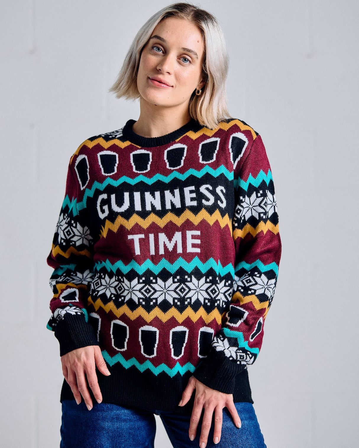 Person wearing a colorful sweater with 'Guinness Time' text against a plain background