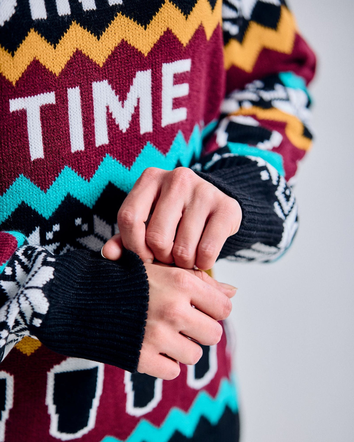 Colorful sweater with 'Good Time' text and pattern, worn by a person.