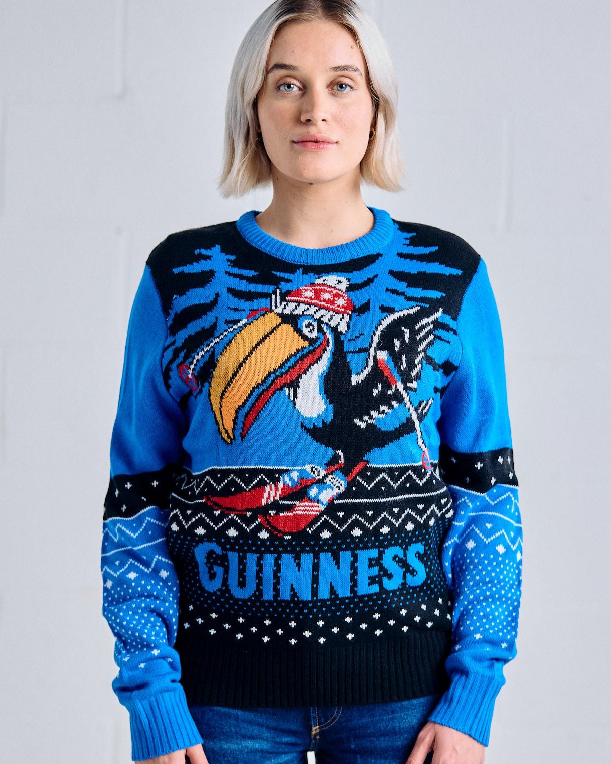 Person wearing a blue Guinness sweater with a toucan design against a white background