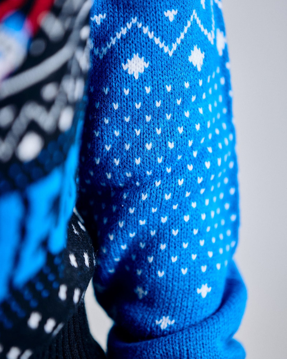 Close-up of a blue knitted sweater with white patterns on a plain background