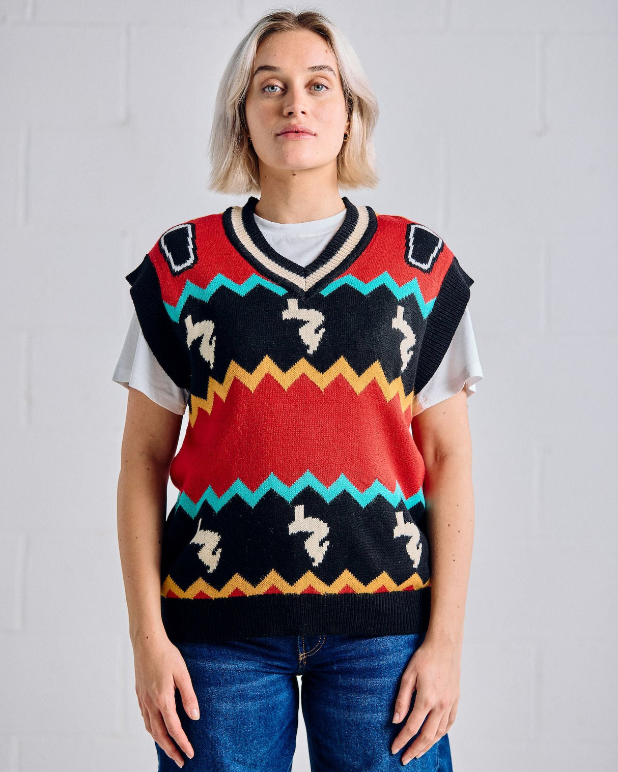 Person wearing a colorful patterned sweater vest against a plain background