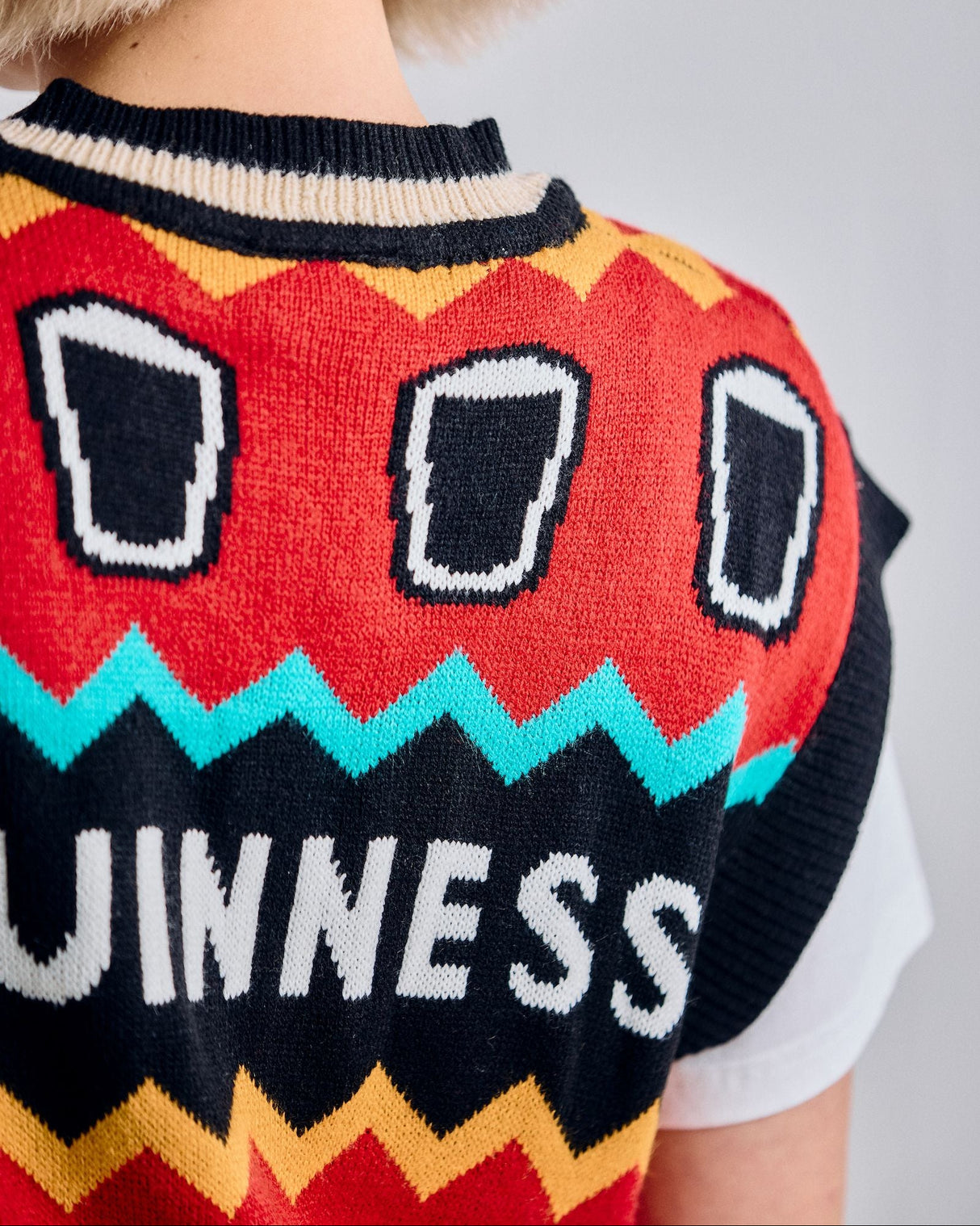 Person wearing a colorful Guinness sweater with a plain background