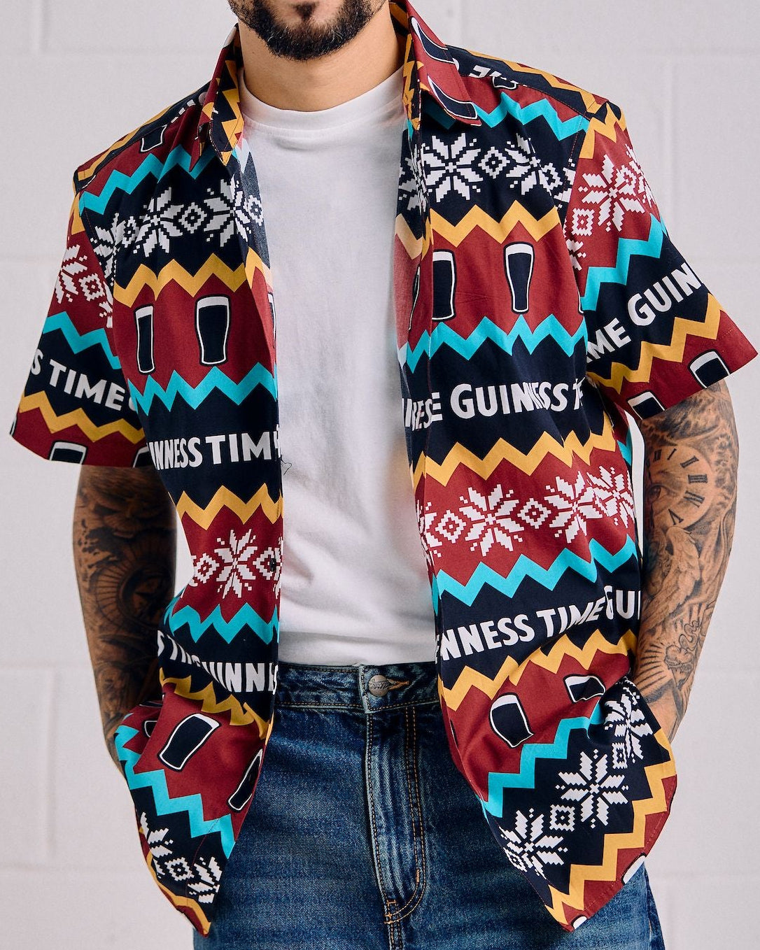 Man wearing a colorful patterned shirt over a white t-shirt with a plain background