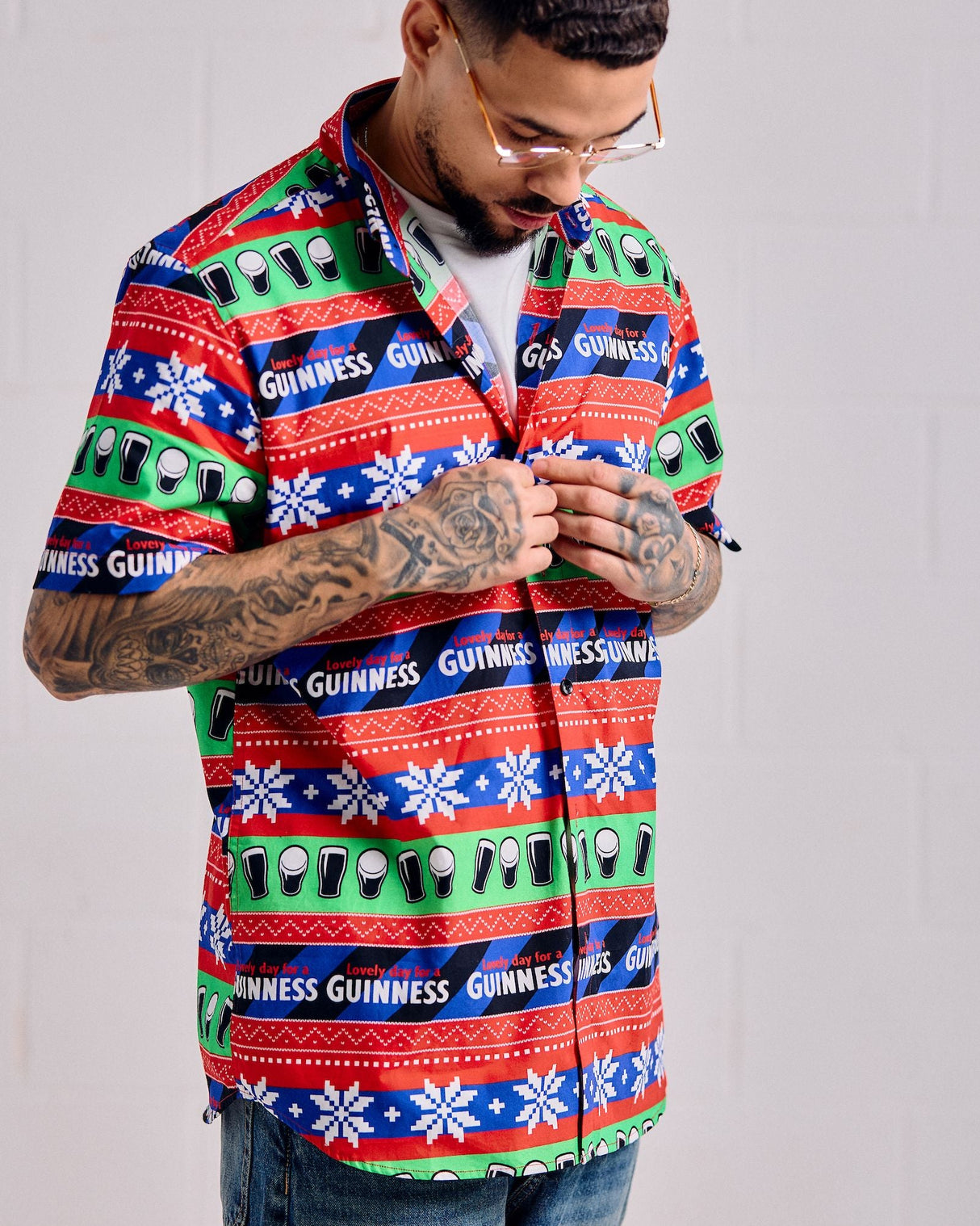 Man wearing a colorful Guinness patterned shirt against a gray background
