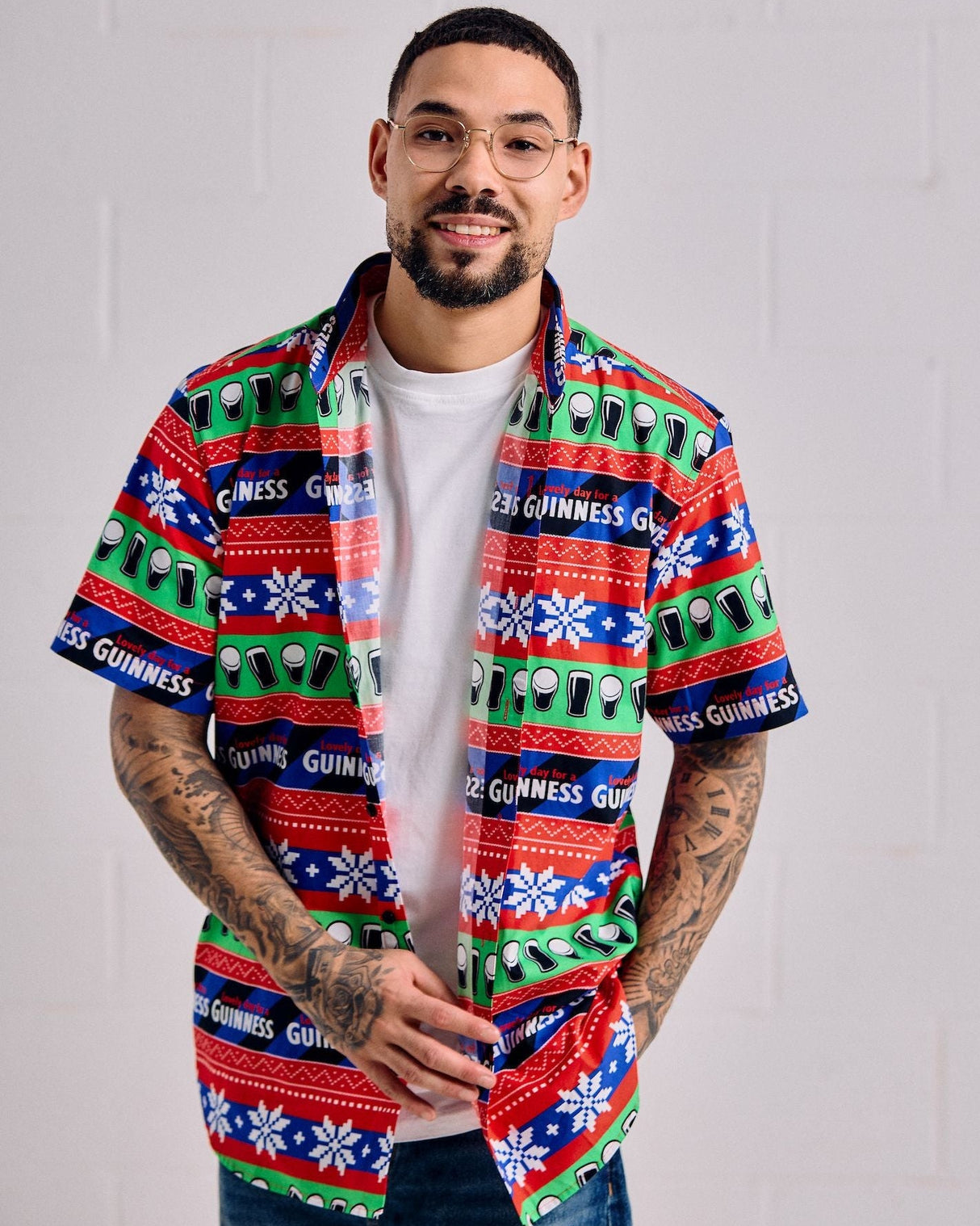 Man wearing a colorful patterned shirt with visible branding against a plain background
