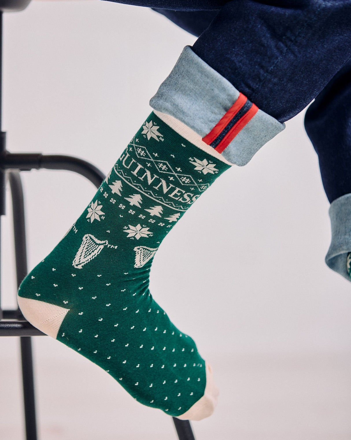 Green sock with white patterns and text, worn by a person sitting on a chair.