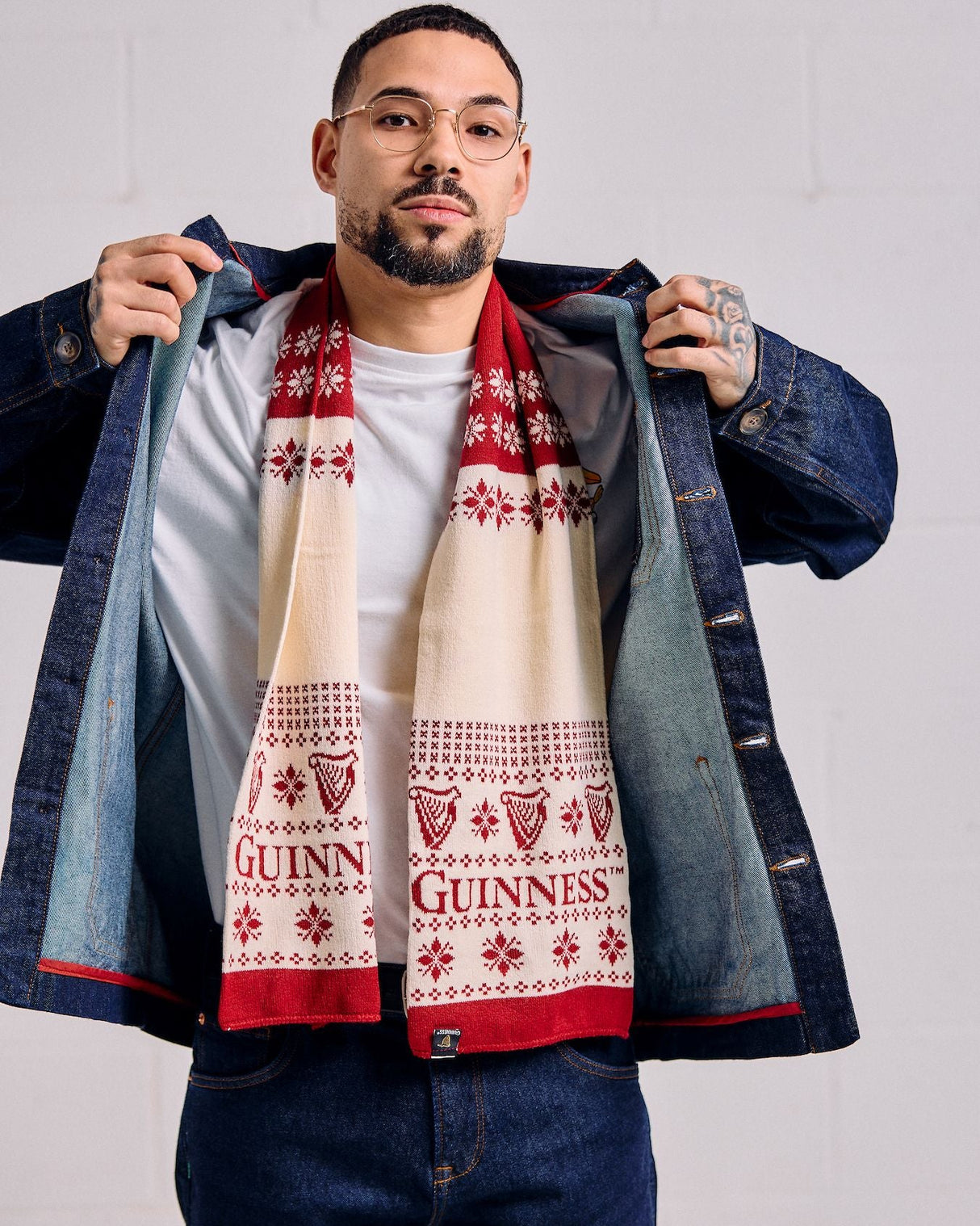 Man wearing a denim jacket and Guinness scarf against a white background