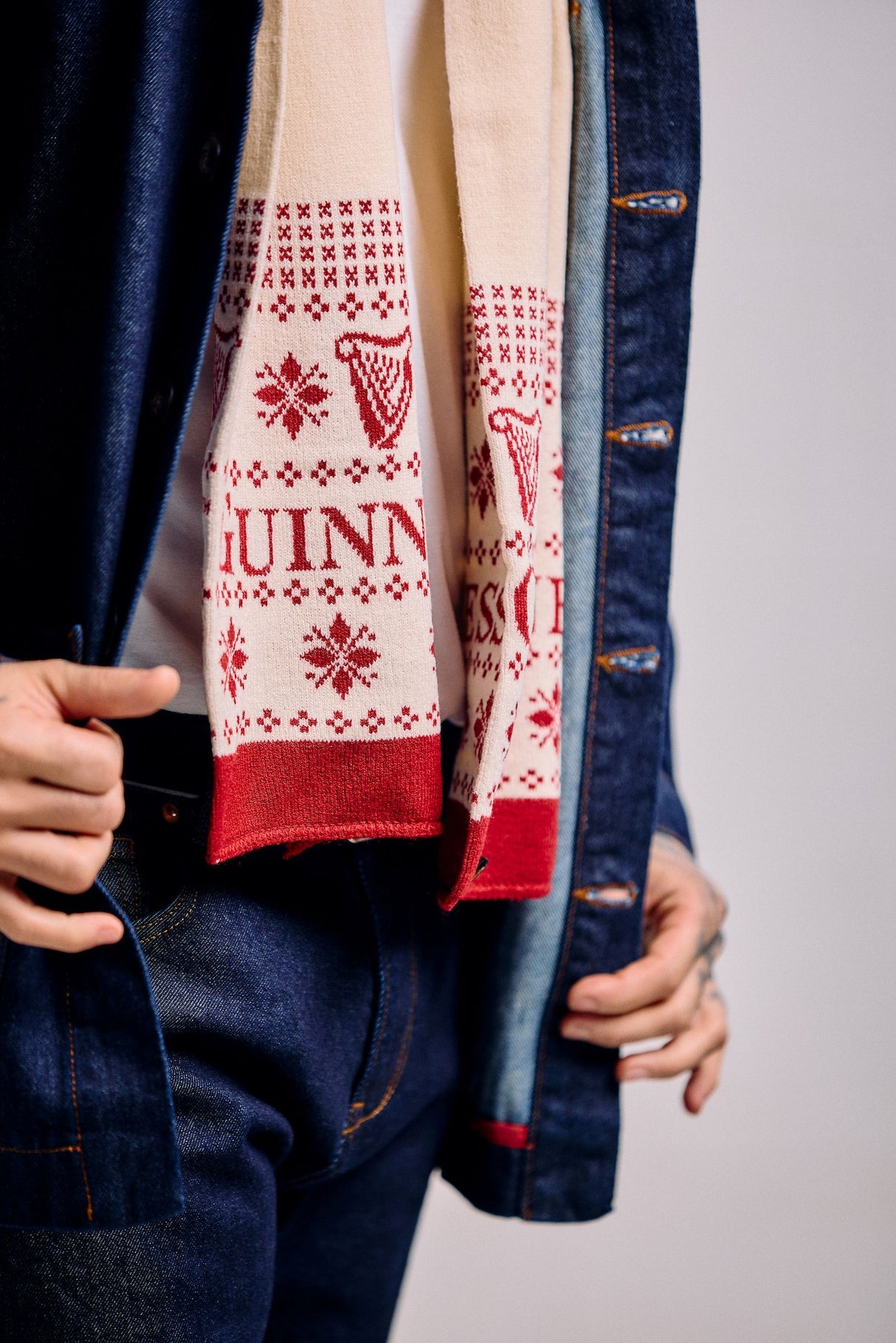 Person wearing a blue denim jacket with a patterned red and white scarf.