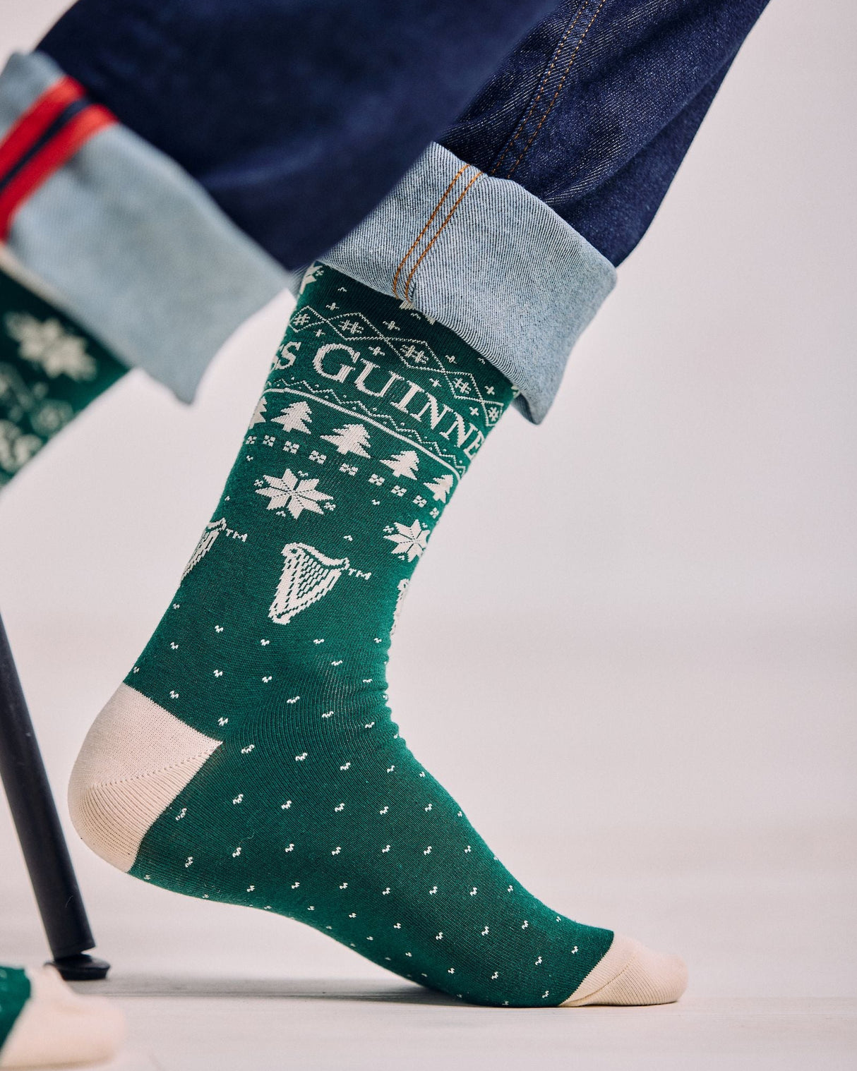 Green sock with Guinness logo worn by a person on a light gray background