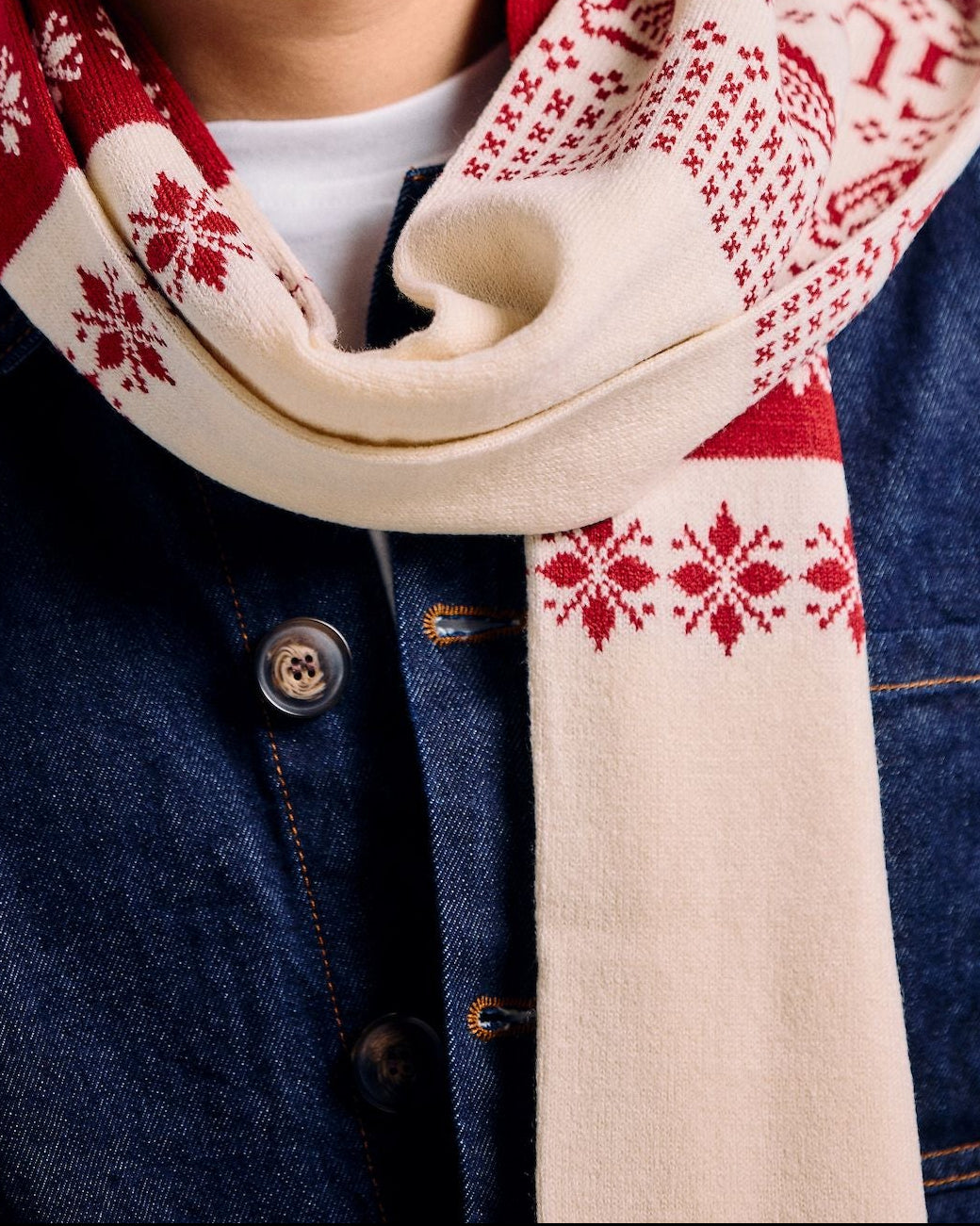 Man wearing a patterned scarf and glasses against a plain background