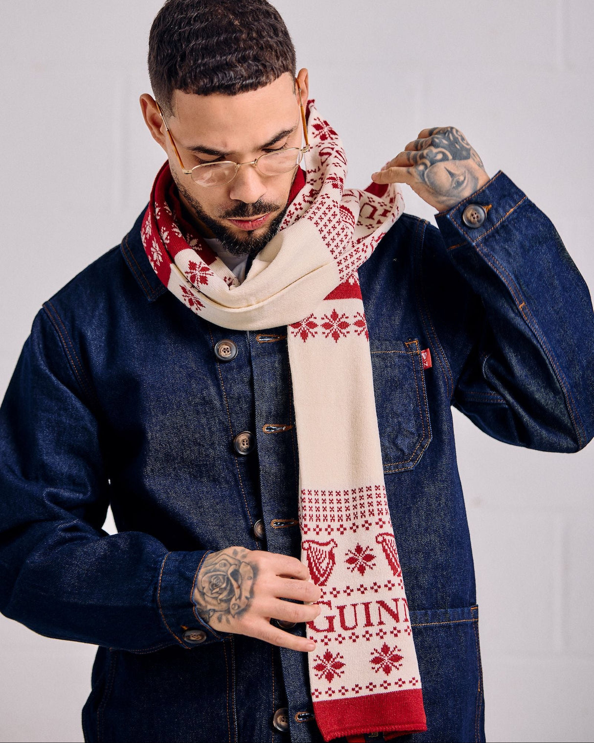 Man wearing a patterned scarf with 'Guinness' branding against a plain background