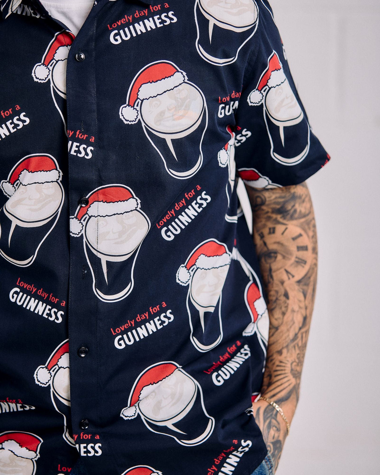 Navy blue shirt with Guinness beer and Santa hats pattern on a plain background