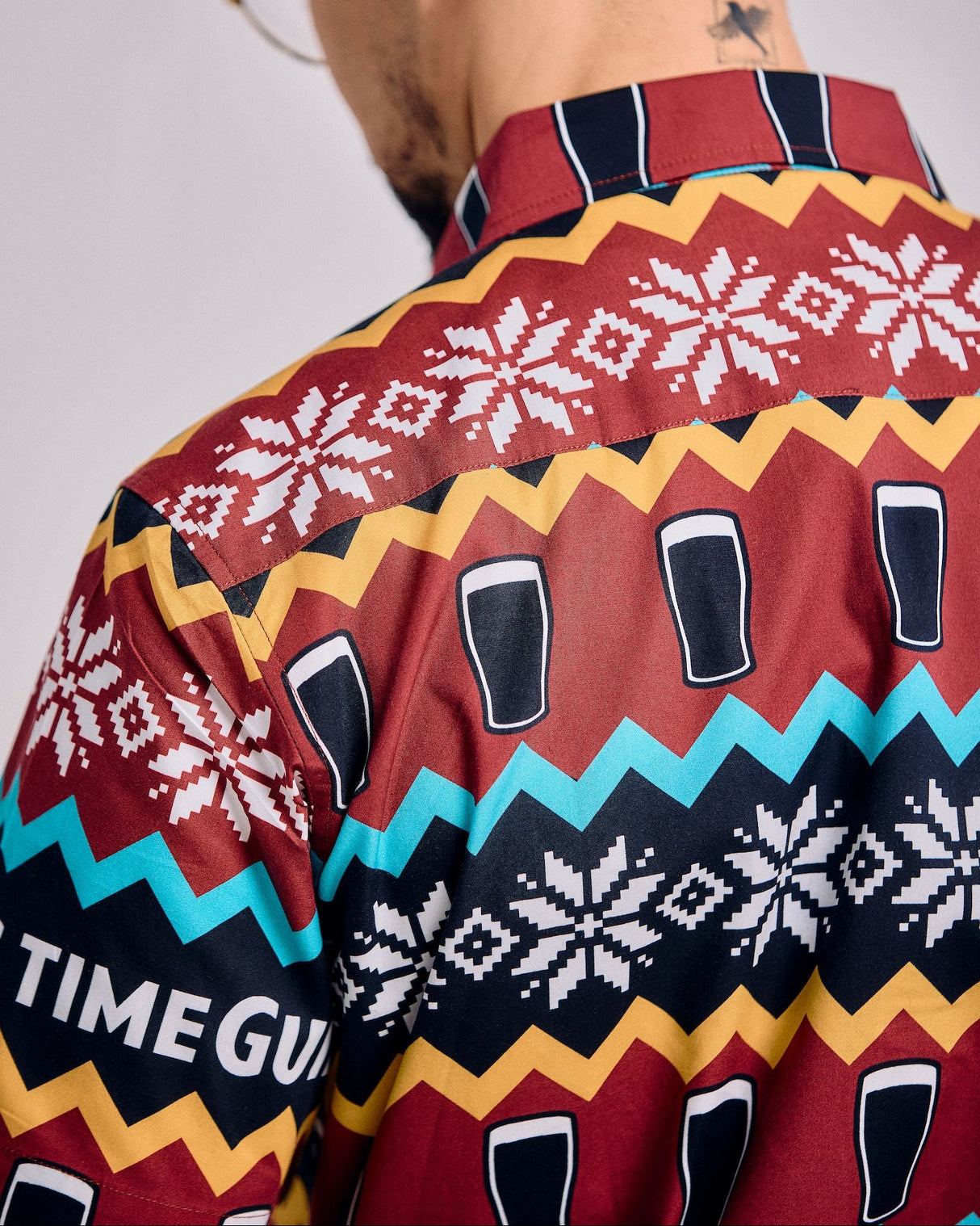 Person wearing a colorful patterned shirt with geometric designs and text.