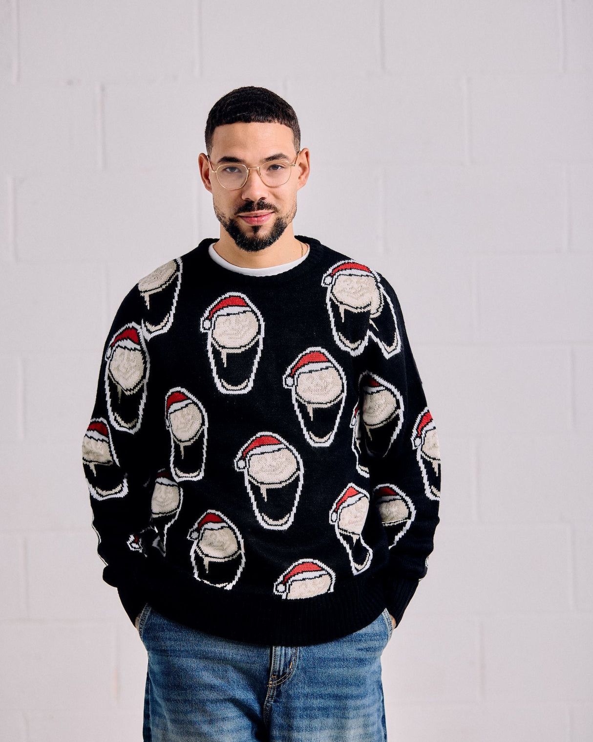 Man wearing a black sweater with Santa Claus face patterns against a white background