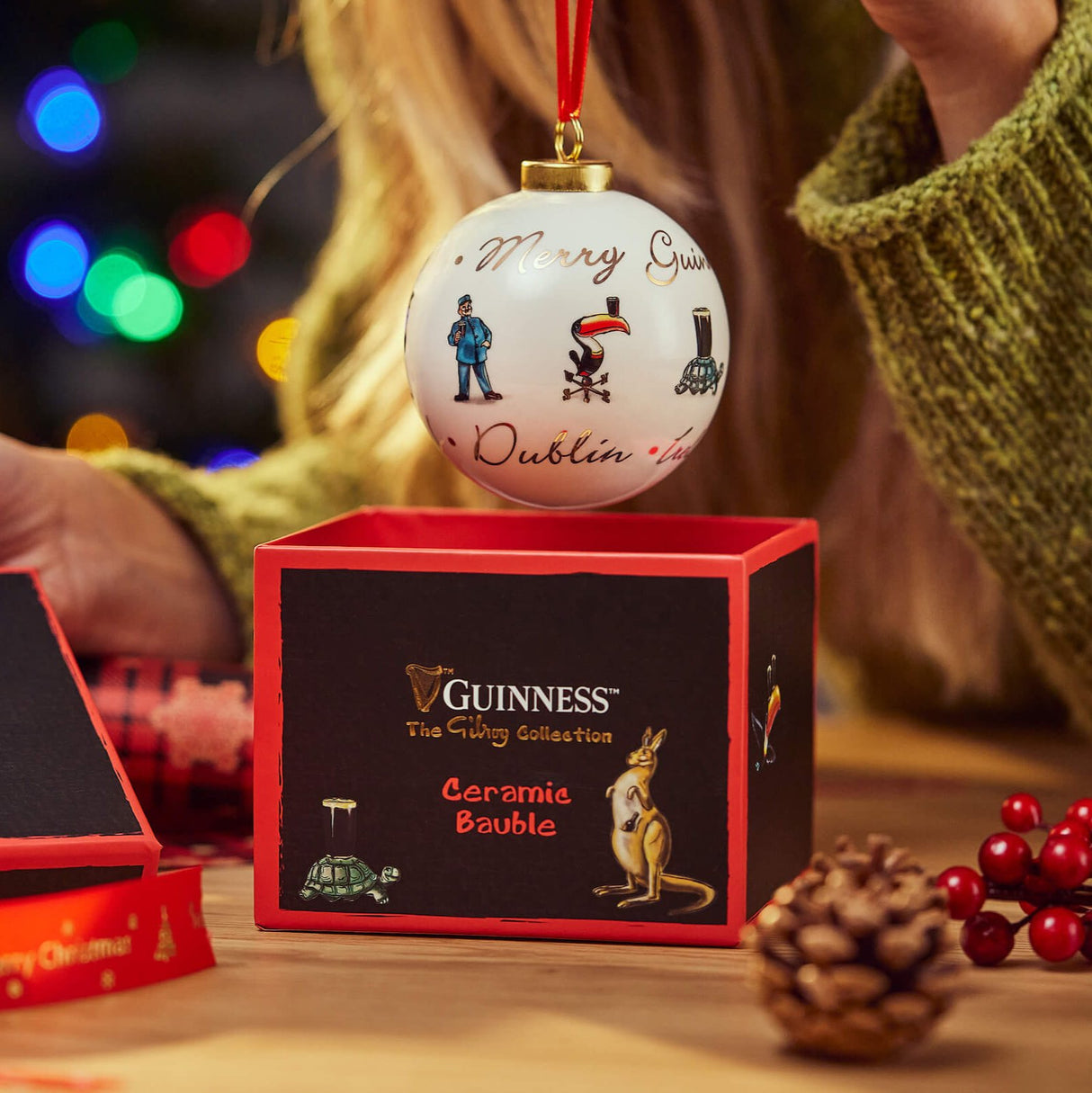 Image of a girl holding up a Guinness Gilroy Christmas Bauble out of its gift box