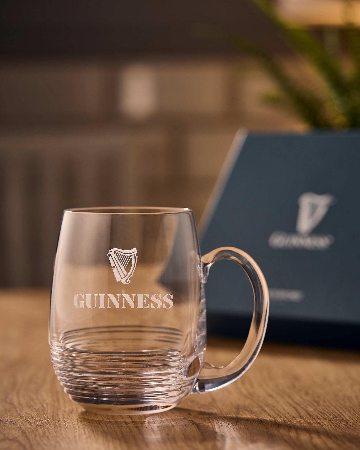 Clear Guinness mug on a wooden surface with a blurred background