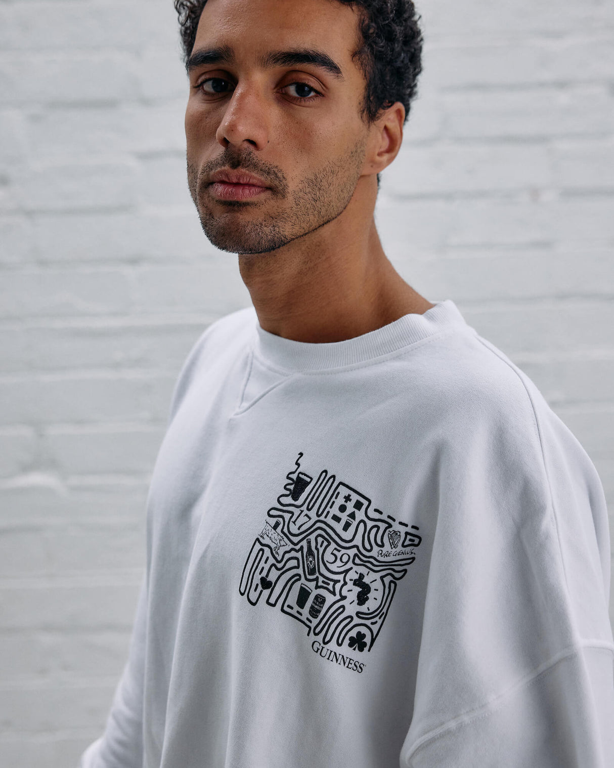 Model wearing the Guinness Storehouse Exclusive white Sweater with stylized Dublin map.