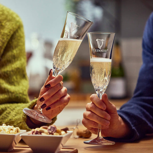 2 people drinking a glass of prosecco in a limited edition Guinness X Waterford crystal flute glasses.