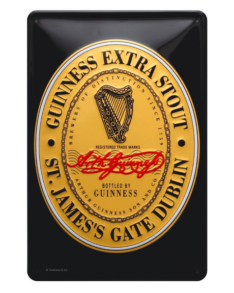 A rectangular metal sign with a black background featuring a central graphic of the GUINNESS Extra Stout Label, with gold and red text, a harp emblem, and the signature of Arthur Guinness.