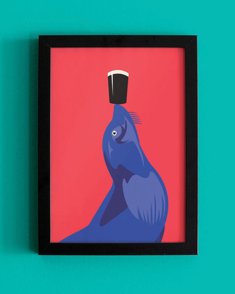 Framed artwork of a blue sealion with a black and white object on its head against a red background