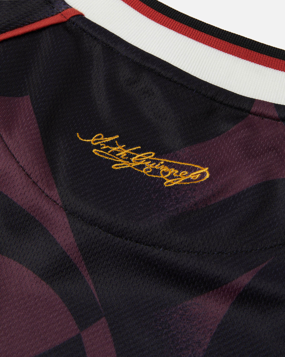 Close-up of a sports jersey with a signature on the collar against a dark background.